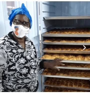 Vó Tutu ao lado do forno com bandejas de pães